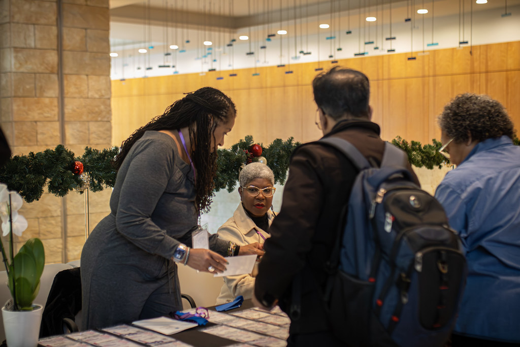 Council program participants exchanging materials and speaking at a welcome table